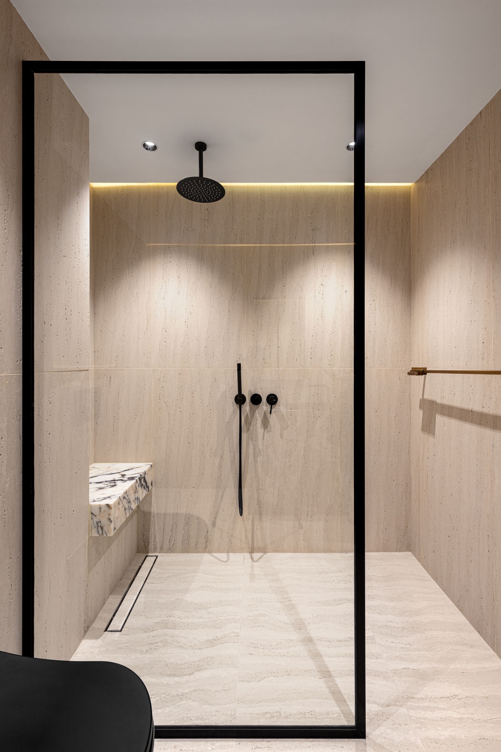 A glass-panelled walk-in shower with a rainfall head and a recessed, lit niche